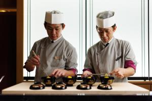 dos chefs de pie en una cocina preparando comida en Yado Shiontei en Yonago