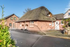 a pink house with a thatched roof on a street at Jules Reetdachkate in Mildstedt
