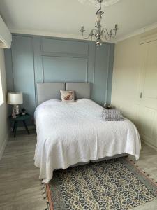 Schlafzimmer mit einem weißen Bett und einem Kronleuchter in der Unterkunft Entire Home between London and Kent- Mulberry House in Kent