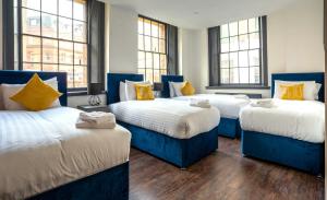 three beds in a room with windows at The Cavern Quarter Aparthotel by UStay in Liverpool