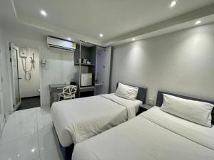 a hotel room with two beds and a bathroom at My Hotel Pratunam in Bangkok