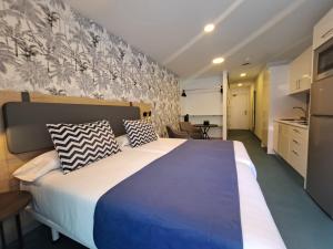 a bedroom with a large bed and a kitchen at RK Farallón Canteras in Las Palmas de Gran Canaria