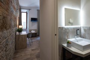 baño con lavabo blanco y pared de ladrillo en B&B Governo dei Nove, en Siena