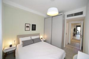 a white bedroom with a white bed and a hallway at Gorgeous - Red rock and Sea view. in Eilat