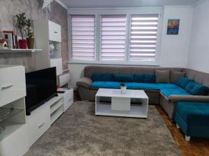 sala de estar con sofá azul y TV en Agape apartman en Višegrad