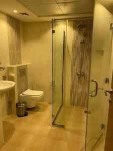 a bathroom with a toilet and a glass shower at Alsahwa Hotel in Seeb