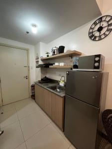 a kitchen with a refrigerator and a clock on the wall at Lovely 1BR Condo @ SM Southmall w/ Netflix & High Speed WIFI in Manila
