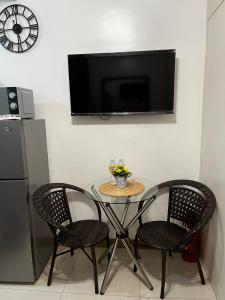a table with two chairs and a television on a wall at Lovely 1BR Condo @ SM Southmall w/ Netflix & High Speed WIFI in Manila