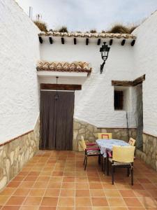 eine Terrasse mit einem Tisch und Stühlen vor einem Gebäude in der Unterkunft Cuevas Baza in Baza