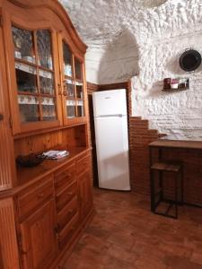 cocina con nevera blanca y armarios de madera en Cuevas Baza, en Baza