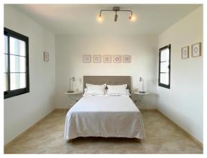 a bedroom with a large white bed with two tables at Villa Sevilla in Playa Blanca