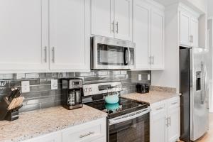 a kitchen with white cabinets and stainless steel appliances at Cool Breeze in Gulf Shores +27 photos