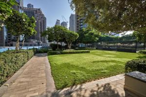 ein Park mit Rasen, Bäumen und Gebäuden in der Unterkunft Magnificent Stunning 2 BR Apartment with Burj Khalifa View in Dubai