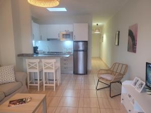 a living room with a couch and a kitchen with a refrigerator at Apartamento El Poril in Tías