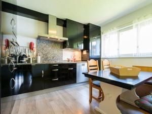 una cocina con armarios negros, mesa y sillas en Beautiful holiday home in Fieschertal with garden, en Fieschertal