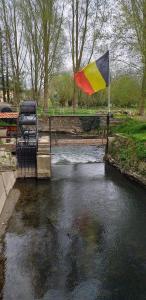 flaga pływająca obok rzeki z mostem w obiekcie Moulin De Moxhe micro gîte et gîte - Bed & Dreams w mieście Moxhe