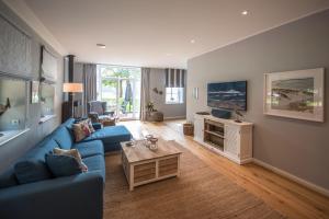ein Wohnzimmer mit einem blauen Sofa und einem TV in der Unterkunft Forsthaus Gödens in Friedeburg