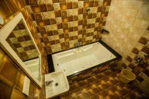 y baño con bañera, lavabo y espejo. en Sri Balaji Villas en Pondicherry