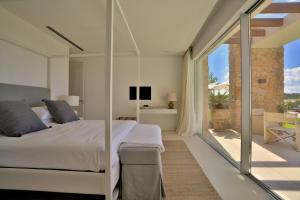 ein Schlafzimmer mit einem Bett und einer Glasschiebetür in der Unterkunft Contemporary Ibizan Villa Cala Conta Dream Short Walk To Beach San Jose in Cala Comte + 32 Fotos