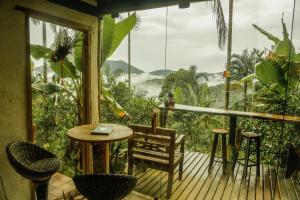 a porch with a table and chairs and a view of the mountains at Eco Hostel organic life in Trindade
