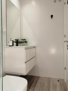 a white bathroom with a toilet and a shower at Dindurra Gijón Centro-Parking gratuito in Gijón