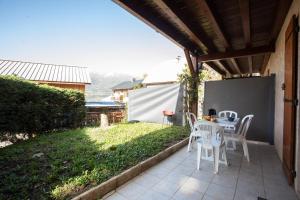 un patio con sillas blancas, mesa y césped en La Durance - 1 chambre Terrasse et Jardin, en Saint-André-dʼEmbrun