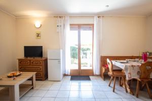 a kitchen with a table and a refrigerator and a television at La Durance - 1 chambre Terrasse et Jardin in Saint-André-dʼEmbrun