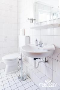 Baño blanco con lavabo y aseo en Memory Hotel en Braunlage