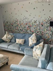 a living room with a blue couch and a flower wall at Ulverston first floor apartment with roof terrace in Ulverston