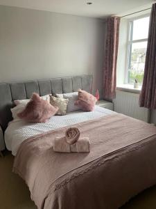 ein Bett mit rosa Kissen und einem Handtuch darauf in der Unterkunft Ulverston first floor apartment with roof terrace in Ulverston