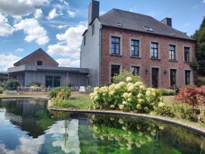 un gran edificio de ladrillo con un estanque delante de él en Gite avec piscine La Buissiere - Fernelmont, en Pontillas