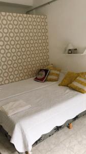 ein großes Bett mit einer weißen Bettdecke und einer Wand in der Unterkunft Tajy - Monoambiente - Barrio Residencial in Corrientes