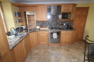 a kitchen with wooden cabinets and a stove top oven at Ulverston Centre Superb 3 Double Bedroom Apartment in Ulverston