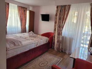 een slaapkamer met een bed, een televisie en gordijnen bij Pension Tui in Sinaia