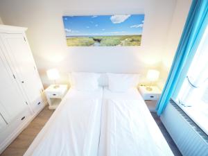 a white bedroom with a bed with two pillows at Haus Neptun App. 4 in Westerland (Sylt)