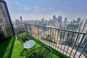 d'un balcon avec deux chaises et une table et vue sur la ville. dans l'établissement Magnificent Lux 2 BR with Incredible Skyline View, à Dubaï