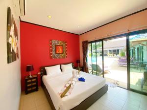 a bedroom with a bed with a red wall at MA MAISON BOUTIQUE HOTEL. in PHUKET in Bang Tao Beach