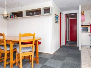 ein Esszimmer mit einem Tisch, Stühlen und einer roten Tür in der Unterkunft 6 person holiday home in Hvide Sande in Nørre Lyngvig