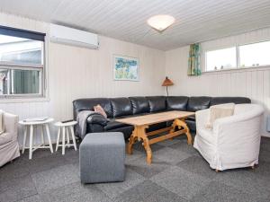 a living room with a black leather couch and a table at 6 person holiday home in Hvide Sande in Nørre Lyngvig