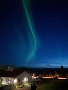 Un uomo in piedi davanti a una casa che osserva l'aurora boreale di Tehúsið Hostel a Egilsstadir