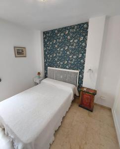 a bedroom with a white bed and a floral wall at Carlos Cañal in Seville