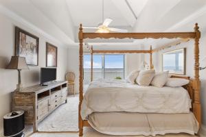 een slaapkamer met een hemelbed en een televisie bij Nautical Club #702 in Atlantic Beach
