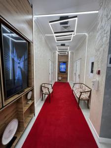 a corridor with a red carpet and chairs and a tv at E-lite& Meatador in Astana