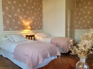 2 camas en una habitación con flores en la pared en Domaine des Longrais, en Saint-Thurial