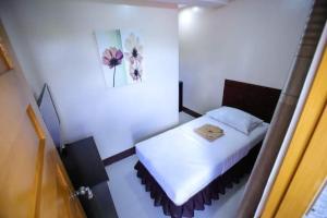 - une petite chambre avec un lit et un tableau mural dans l'établissement Marco s Tourist Inn by RedDoorz, à Leyte