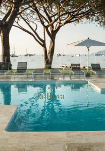 a swimming pool with chairs and an umbrella at Hôtel La Roya in Saint-Florent