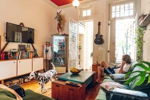 a woman sitting on a couch in a living room with a dog at Discovery Hostel in Rio de Janeiro