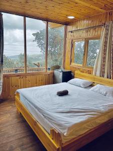 ein Schlafzimmer mit einem großen Bett in einem Zimmer mit Fenstern in der Unterkunft Ajloun Wooden Huts اكواخ عجلون الخشبية Live amid nature in Umm al Manābī‘