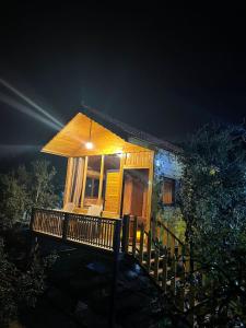a small house with a deck at night at Ajloun Wooden Huts اكواخ عجلون الخشبية Live amid nature in Umm al Manābī‘