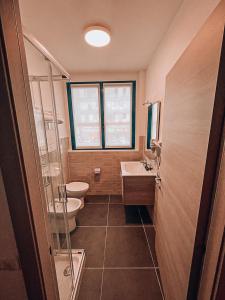 y baño con 2 aseos, lavamanos y ducha. en Blu Hotel, en Buccinasco